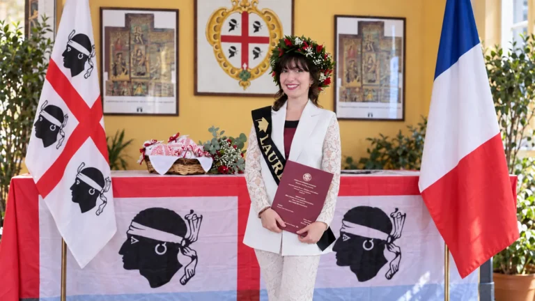 Illustrazione di Federica Idone con la tesi di laurea, tra la bandiera della Sardegna e quella della Francia